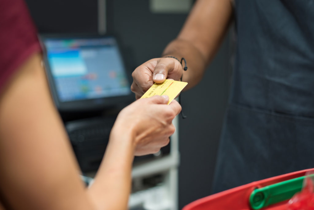 A unified POS system will help keep your font end operations, like in this image of a woman using credit card to pay at supermarket integrated with your back end reports and analytics.