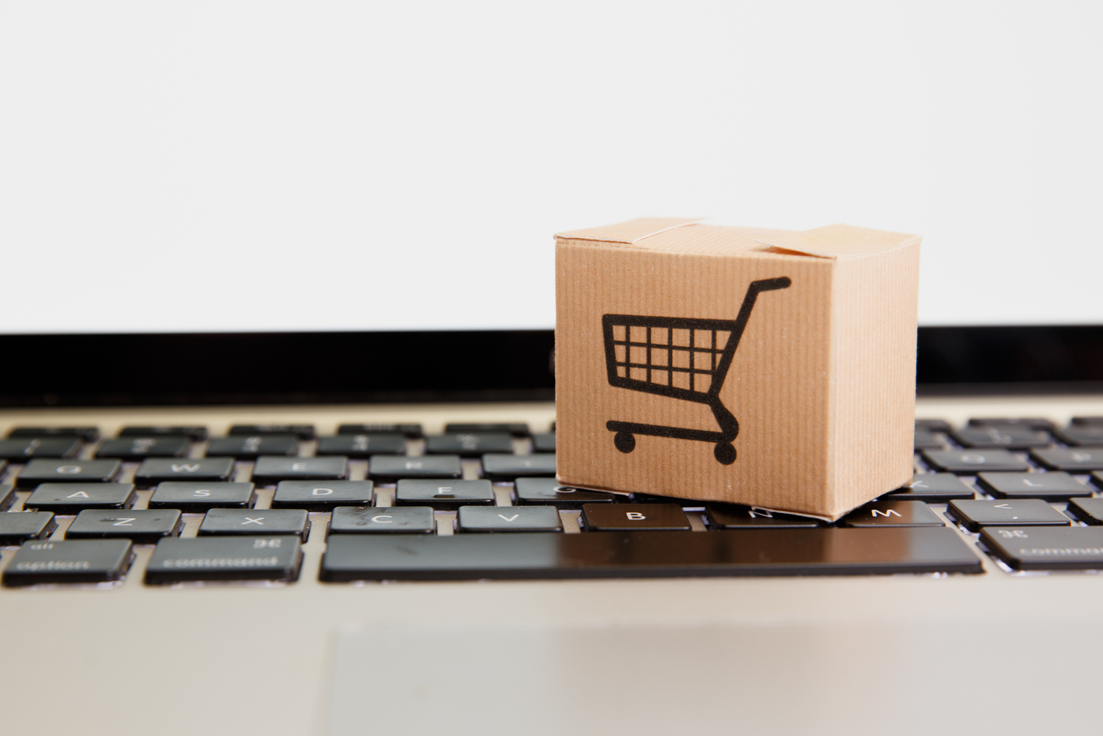 Online shopping . ecommerce and delivery service concept : Paper cartons with a cart or trolley logo on a laptop keyboard, depicts customers order things from retailer sites