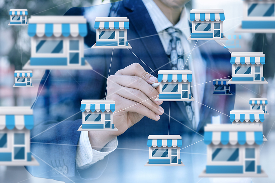 Businessman draws franchise marketing system on blurred background.