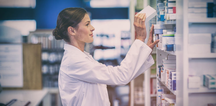 Pharmacist checking medicine in shelf at pharmacy