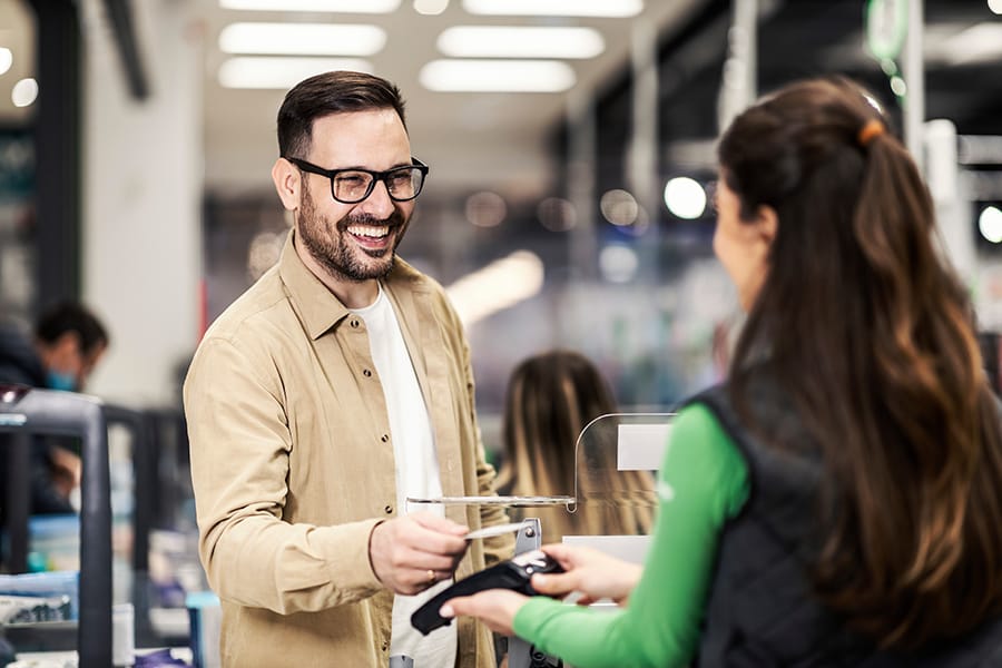 A smiling customer using credit card in supermarket at checkout.