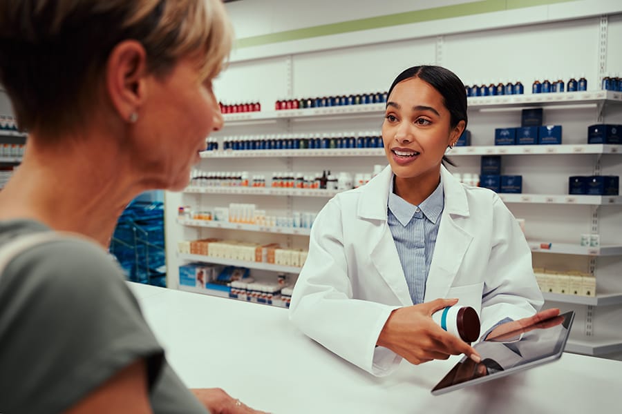 Female pharmacist guiding customer with tablets on digital tablet