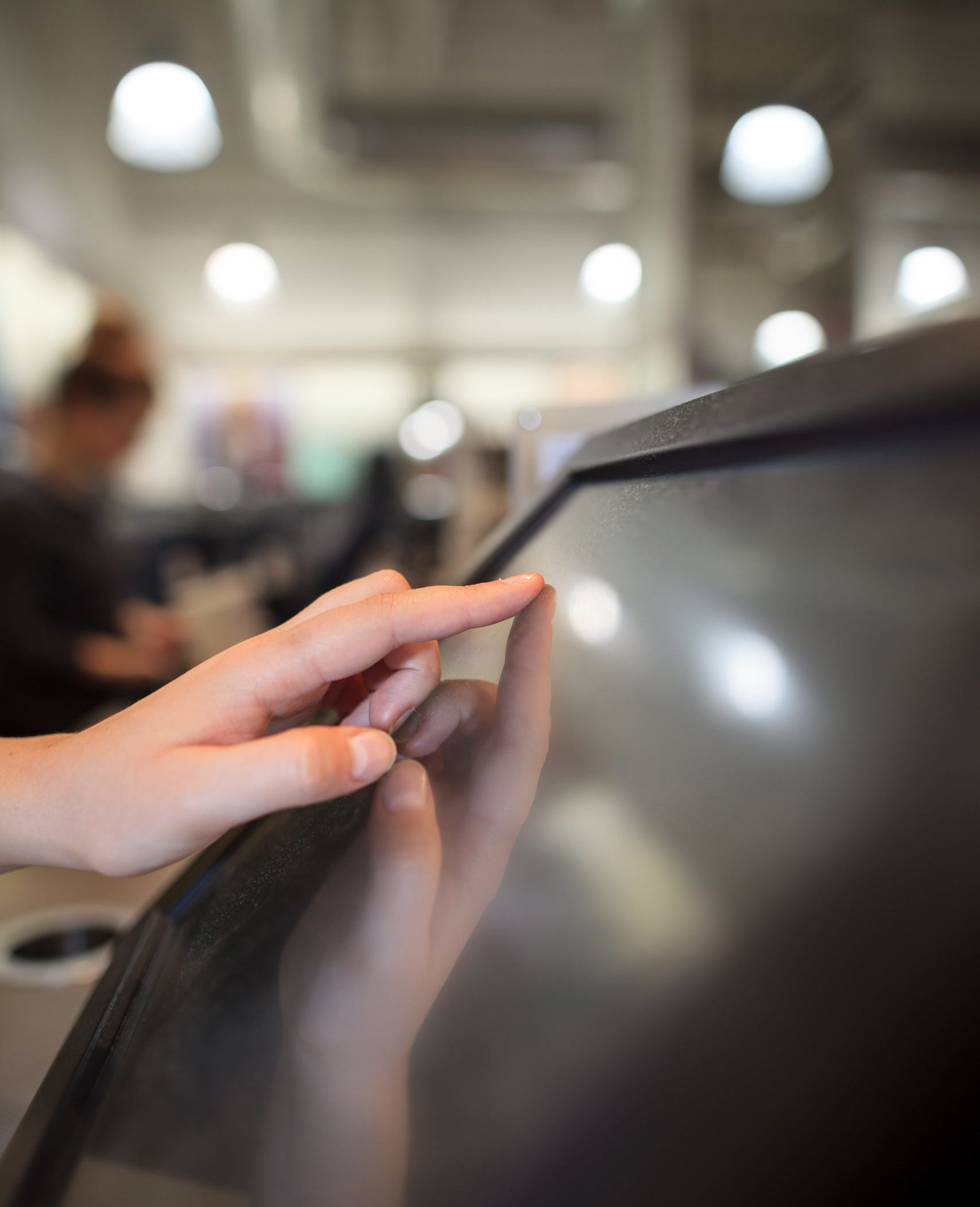 Young woman hand charging a payment for a some clothes by touchscreen treasury at huge shopping centre (color toned image)
