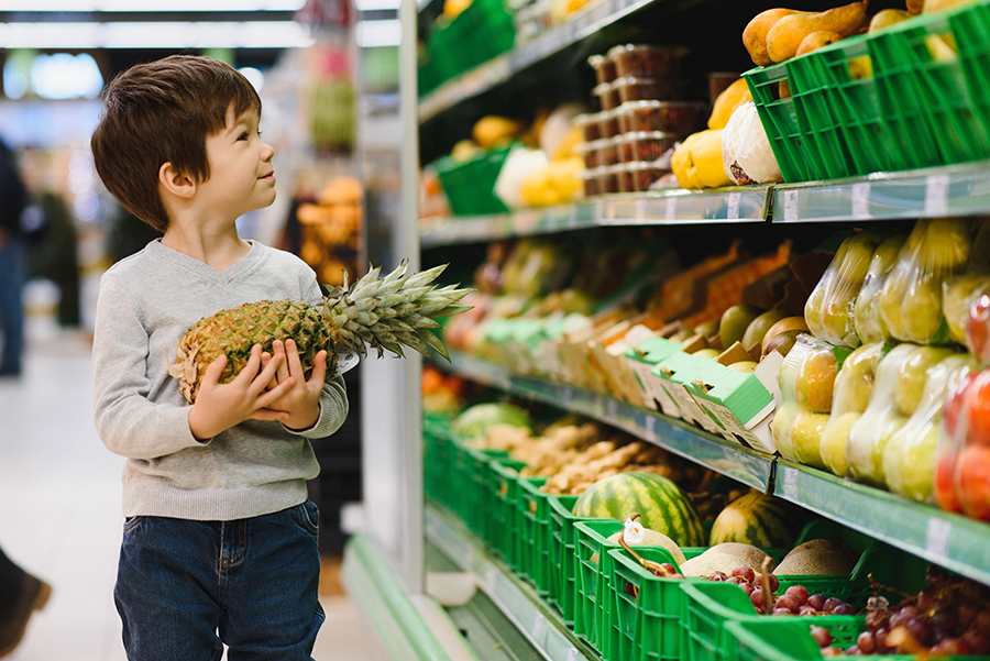 pretty boy with pineapple in supermarket
