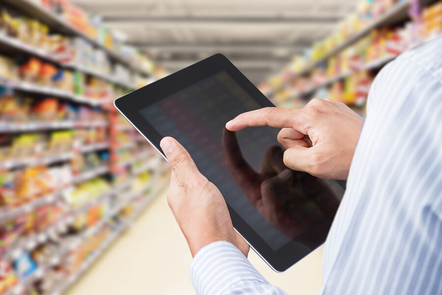 Businessman checking inventory in minimart on touchscreen tablet