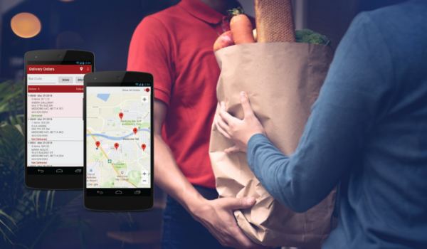 Grocery delivery driver handing a customer a bag of groceries with mobile devices displaying delivery tracking and route management software.