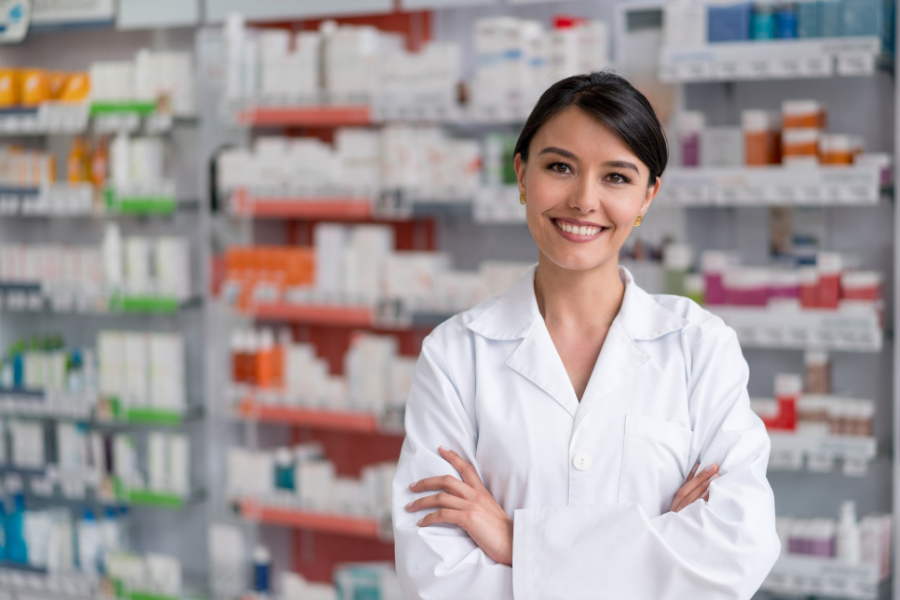 Pharmacist smiling inside a health centre pharmacy, representing modern workflows and POS system efficiency